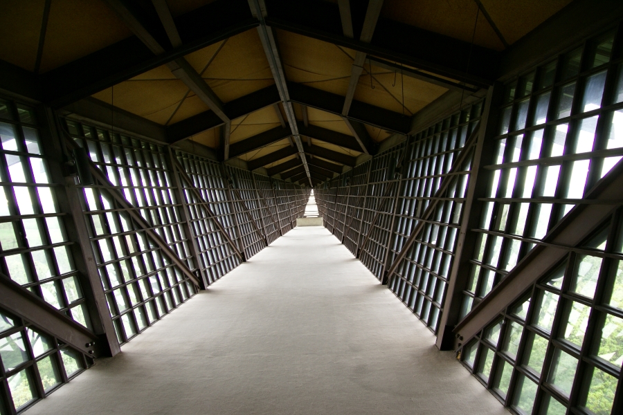 Sloped sides of gridded steel windows below a roof narrow into the distance making it look like the observation deck extends a very long distance